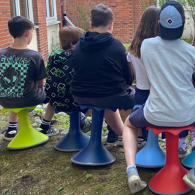 Kinder im Garten auf bunten Kippelstühlen