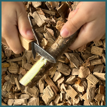Detailansicht von Kinderhänden mit Schnitzmesser.